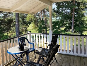 A covered outdoor area with a table and chairs, surrounded by a white railing, overlooking a wooded area. - 4 Person Holiday Home in Horn (Horn)