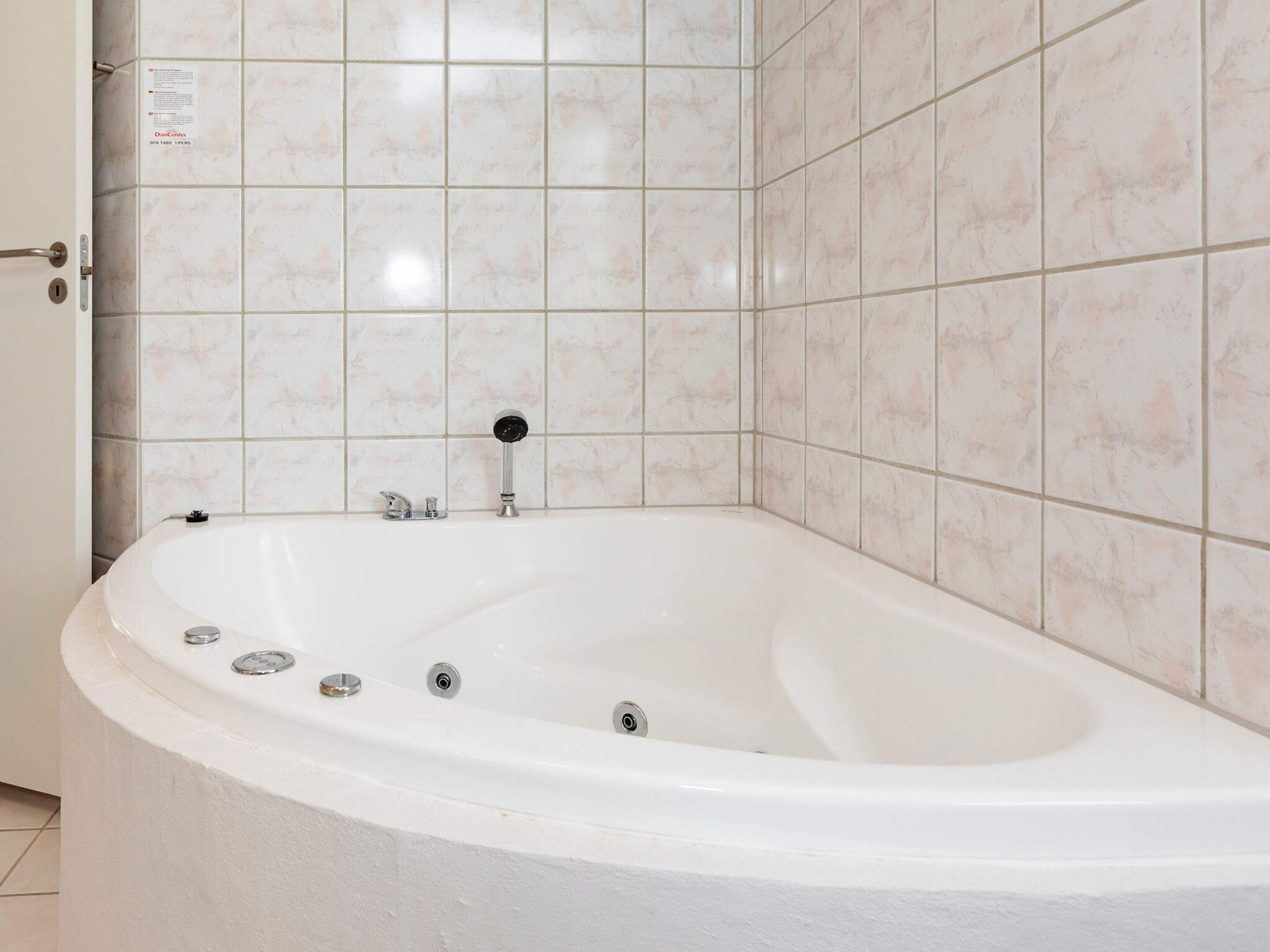 A bathroom with a freestanding bathtub, a door, and tiled walls.