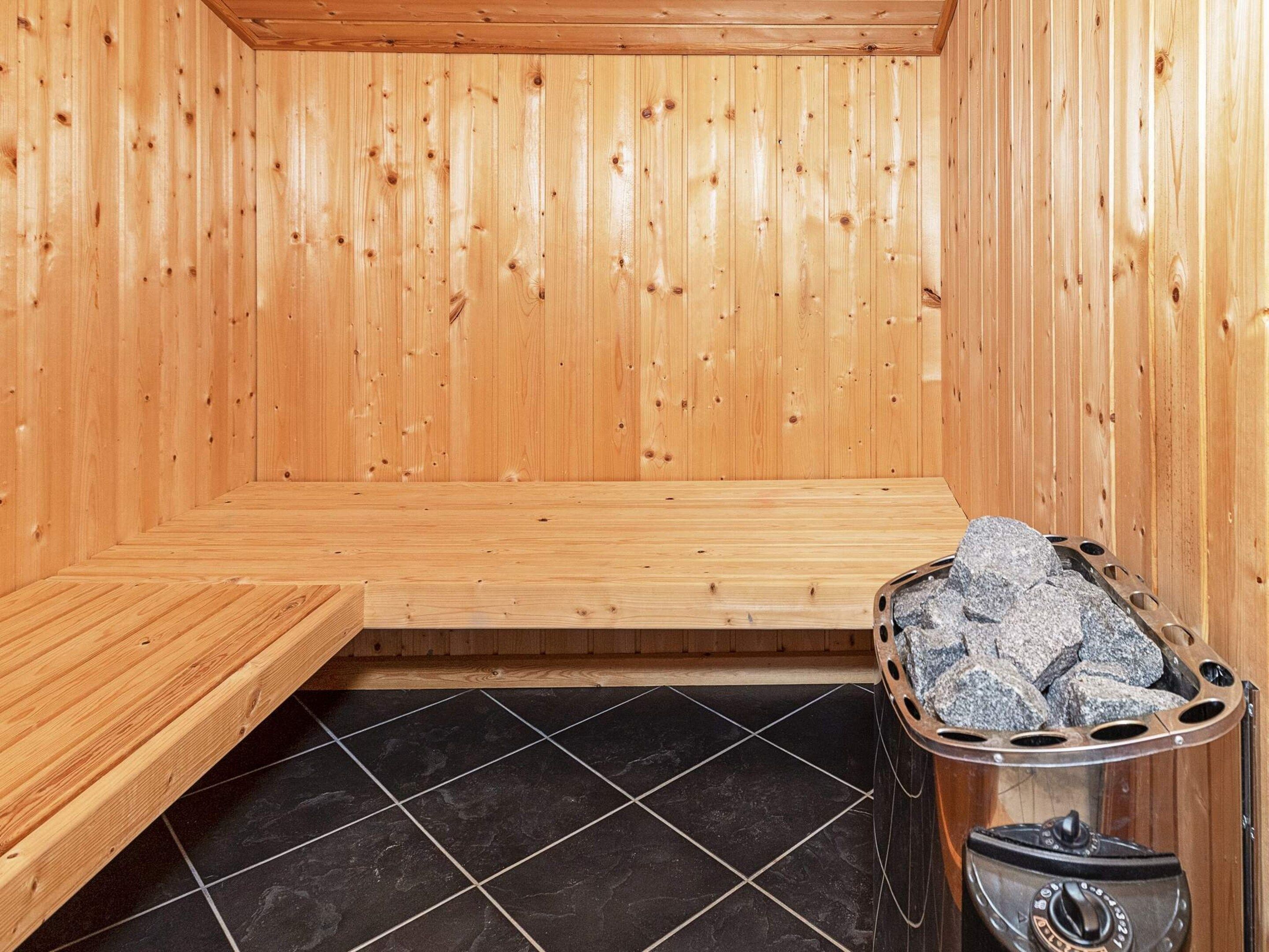 Una sala de sauna con paredes de madera, un banco y suelo de baldosas de piedra.