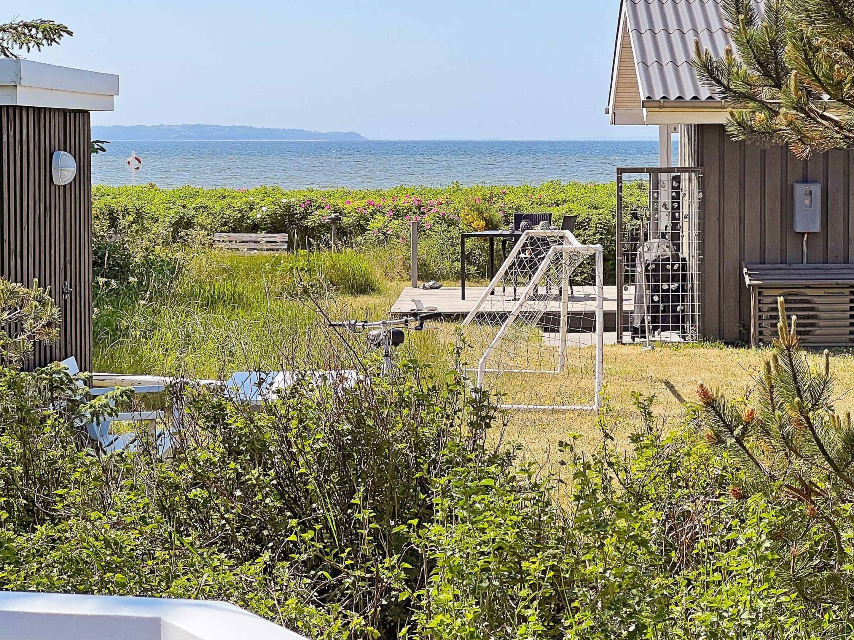Una propiedad costera con vista al mar, una estructura de madera y una reja metálica.
