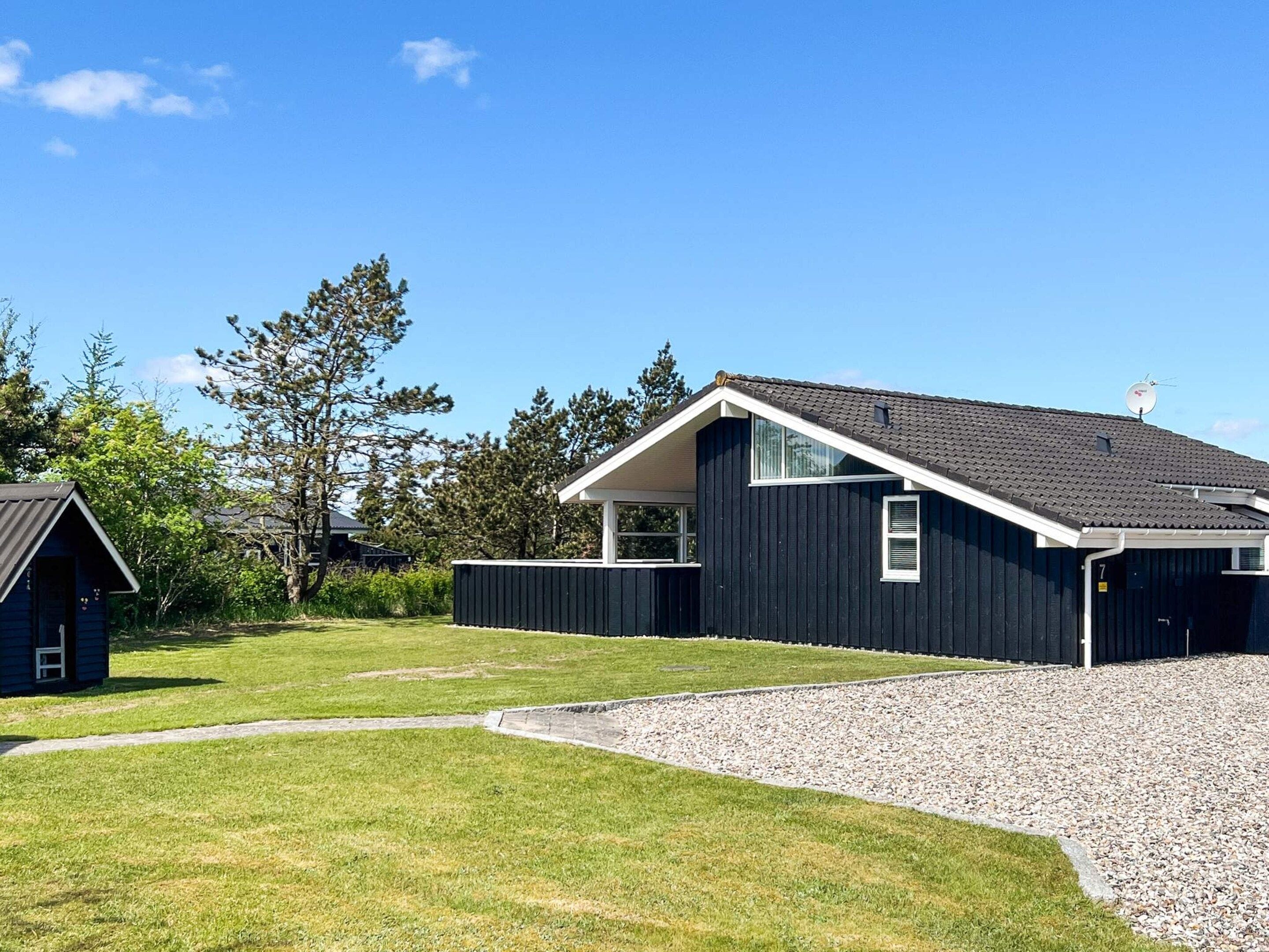 A modern two-story house with a dark exterior, a sloped roof, and a visible satellite dish.