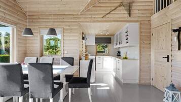 A modern log cabin interior with a dining area, kitchen, and white cabinetry.