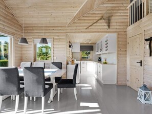 A modern log cabin interior with a dining area, kitchen, and white cabinetry.