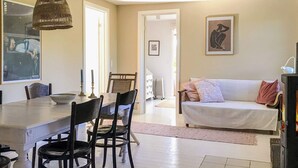 A dining area with a table, chairs, and a hanging light fixture. There is a sofa and a radiator in the background. - 6 Person Holiday Home in Gilleleje (Gilleleje)