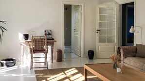 A living room with a sofa, a coffee table, and a chair. There is a door leading to another room. - 6 Person Holiday Home in Gilleleje (Gilleleje)