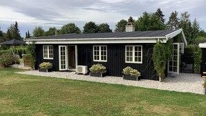 A black house with white trim, a covered porch, and a gravel driveway. - 6 Person Holiday Home in Gilleleje (Gilleleje)