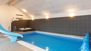 Una piscina interior con tobogán, un jacuzzi y una sauna.