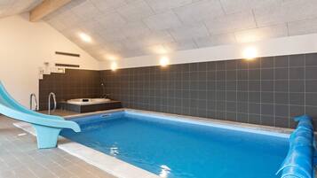 Piscina interna com escorregador, banheira de hidromassagem e sauna.