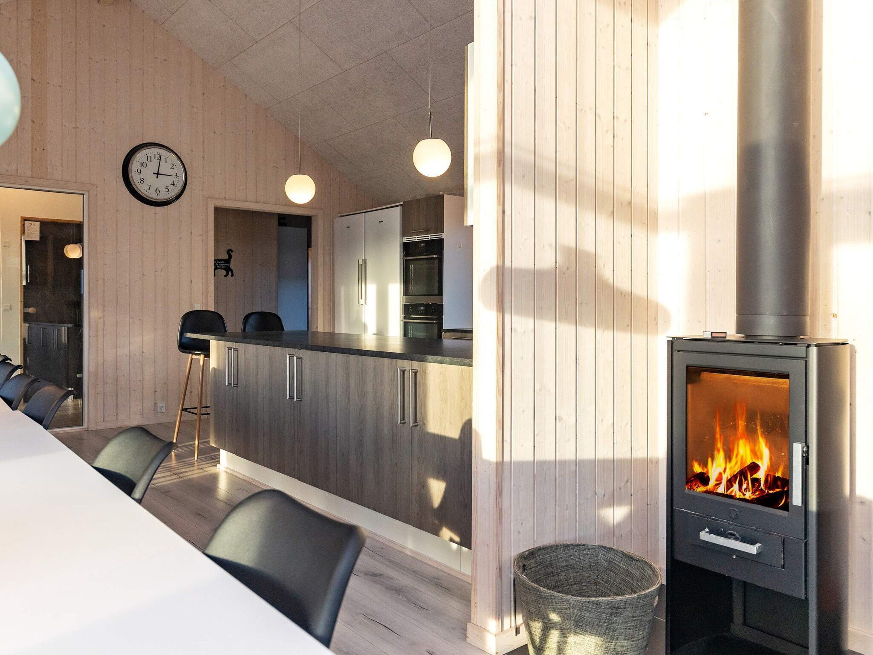 Eine moderne Küche mit Holzausstattung, einer zentralen Kochinsel und einem Kaminofen.