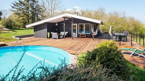 A modern outdoor pool area with a wooden deck, a covered seating area, and a swimming pool. - 6 Person Holiday Home in Ebeltoft (Ebeltoft)