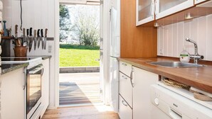 A modern kitchen with white cabinets, a Bosch dishwasher, and a large window opening to a grassy outdoor area. - 6 Person Holiday Home in Ebeltoft (Ebeltoft)