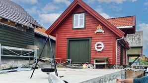 A red building with a window, a door, and a circular sign on the wall. - 6 Person Holiday Home in Hernar (Oygarden)