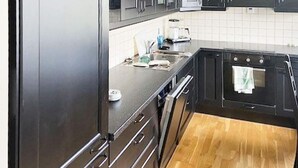 A kitchen with dark cabinets, a stainless steel refrigerator, a wooden countertop, and a built-in oven. - 6 Person Holiday Home in Hernar (Oygarden)