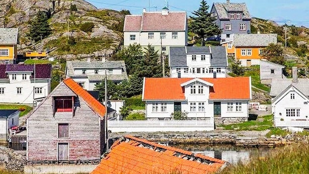 A coastal village with traditional houses, a rocky hill in the background, and a calm body of water in the foreground. - 6 Person Holiday Home in Hernar (Oygarden)