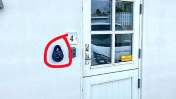 Una puerta blanca con un ventanal, un cartel con el número 4 y un círculo rojo que destaca un objeto azul.