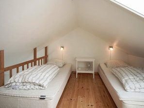 A small attic bedroom with two single beds, a nightstand with a fan, and two wall-mounted lights. - 4 Star Holiday Home in Allinge (Allinge)