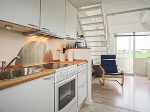A modern kitchen with a stove, sink, and wooden countertop. There is a chair and a ladder leading to a balcony. - 4 Star Holiday Home in Allinge (Allinge)