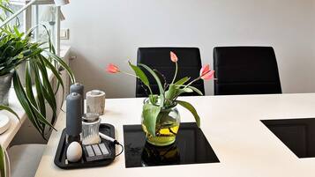 A dining table with a vase of flowers, a salt and pepper set, and a black tray with a white object.