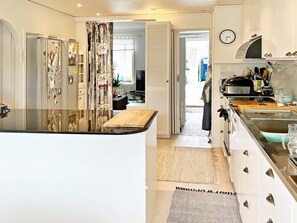 A modern kitchen with a central island, a dining area, and a view into the living room. - 4 Star Holiday Home in Varmdo (Värmdö)