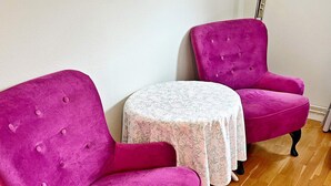 A room with two pink upholstered chairs and a small round table with a floral tablecloth. - 4 Star Holiday Home in Varmdo (Värmdö)
