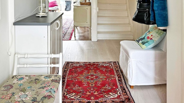 A hallway with a white bench, a red patterned rug, and a white cabinet with a lamp. - 4 Star Holiday Home in Varmdo (Värmdö)