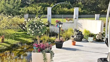 A wooden deck with potted plants and a small pond.