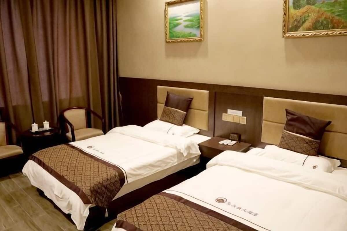 A hotel room with two beds, a nightstand, a chair, and a painting on the wall.