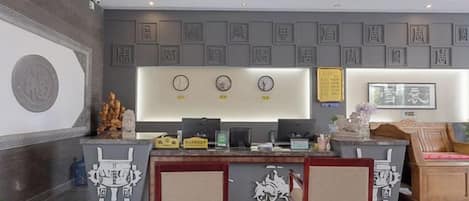 A reception area with a desk, chairs, and a wall with framed items.