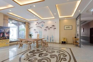 Un moderno vestíbulo de hotel con zona de comedor central, arte decorativo en las paredes y un suelo estampado.
