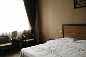 A hotel room with a bed, two chairs, a small table, and a nightstand. - Linjianglou Hotel (Mian County)