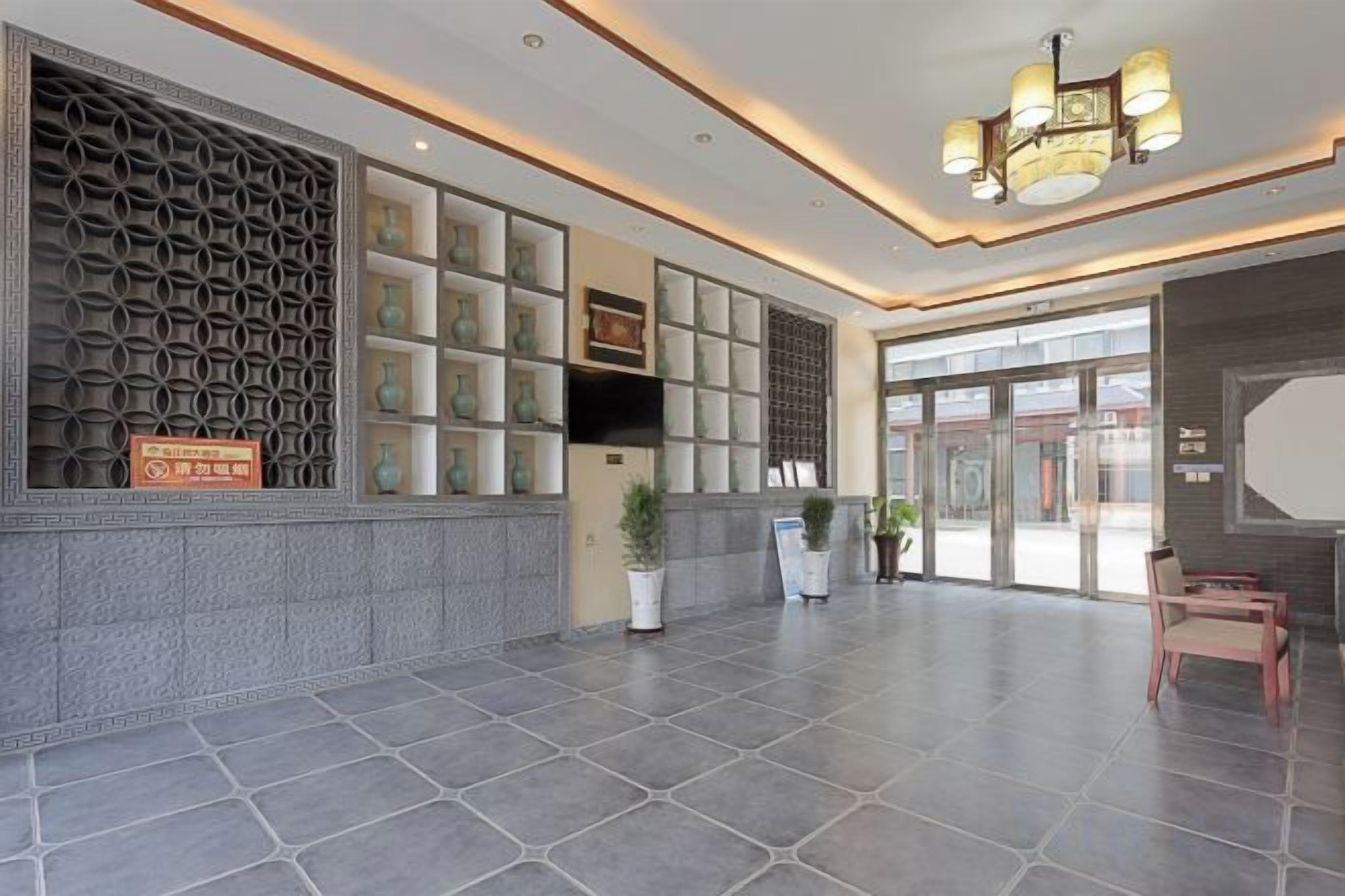 A spacious lobby with a reception desk, seating area, and a patterned wall.