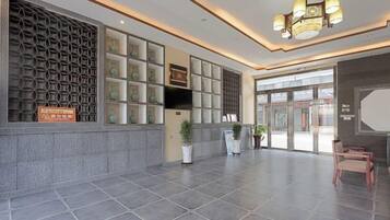 A spacious lobby with a reception desk, seating area, and a patterned wall.