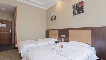 Een hotelkamer met twee bedden, een houten hoofdbord, een deur en een muur met een ingelijst schilderij en een bloemistisch ontwerp.