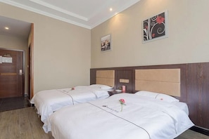 A hotel room with two beds, a wooden headboard, a door, and a wall with a framed picture and a floral design. - Linjianglou Hotel (Mian County)