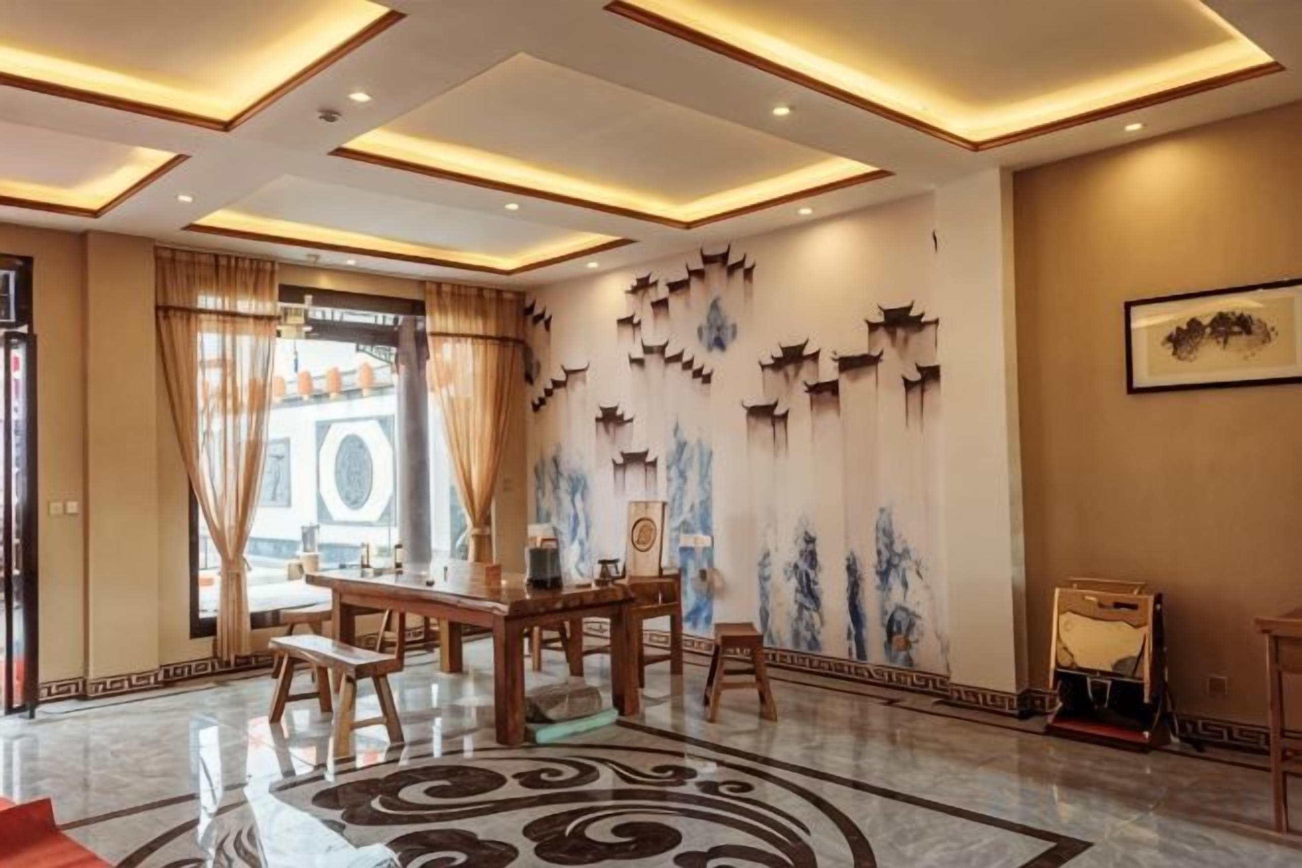 Een hotel lobby met een receptiebalie, een zithoek en decoratieve muurkunst.
