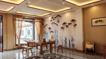 Een hotel lobby met een receptiebalie, een zithoek en decoratieve muurkunst.