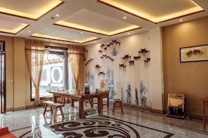 Un vestíbulo de hotel con recepción, zona de estar y decoración mural.