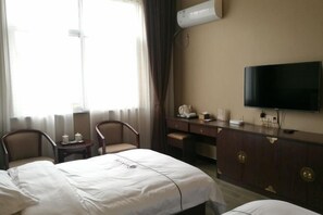 A hotel room with a bed, two chairs, a desk, a television, and a minibar. - Linjianglou Hotel (Mian County)
