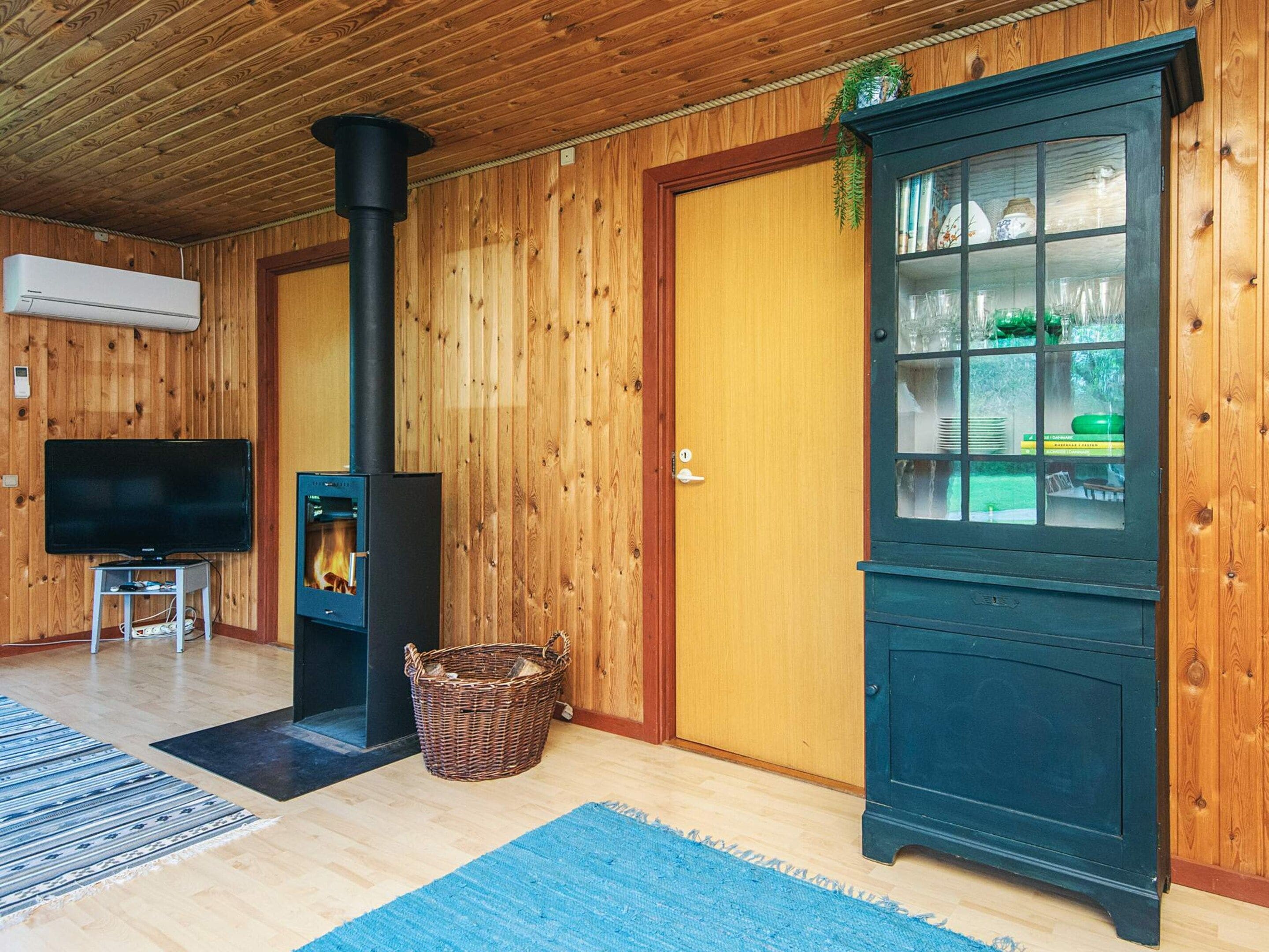 A wooden-paneled room with a television, a fireplace, and a cabinet with glass doors.
