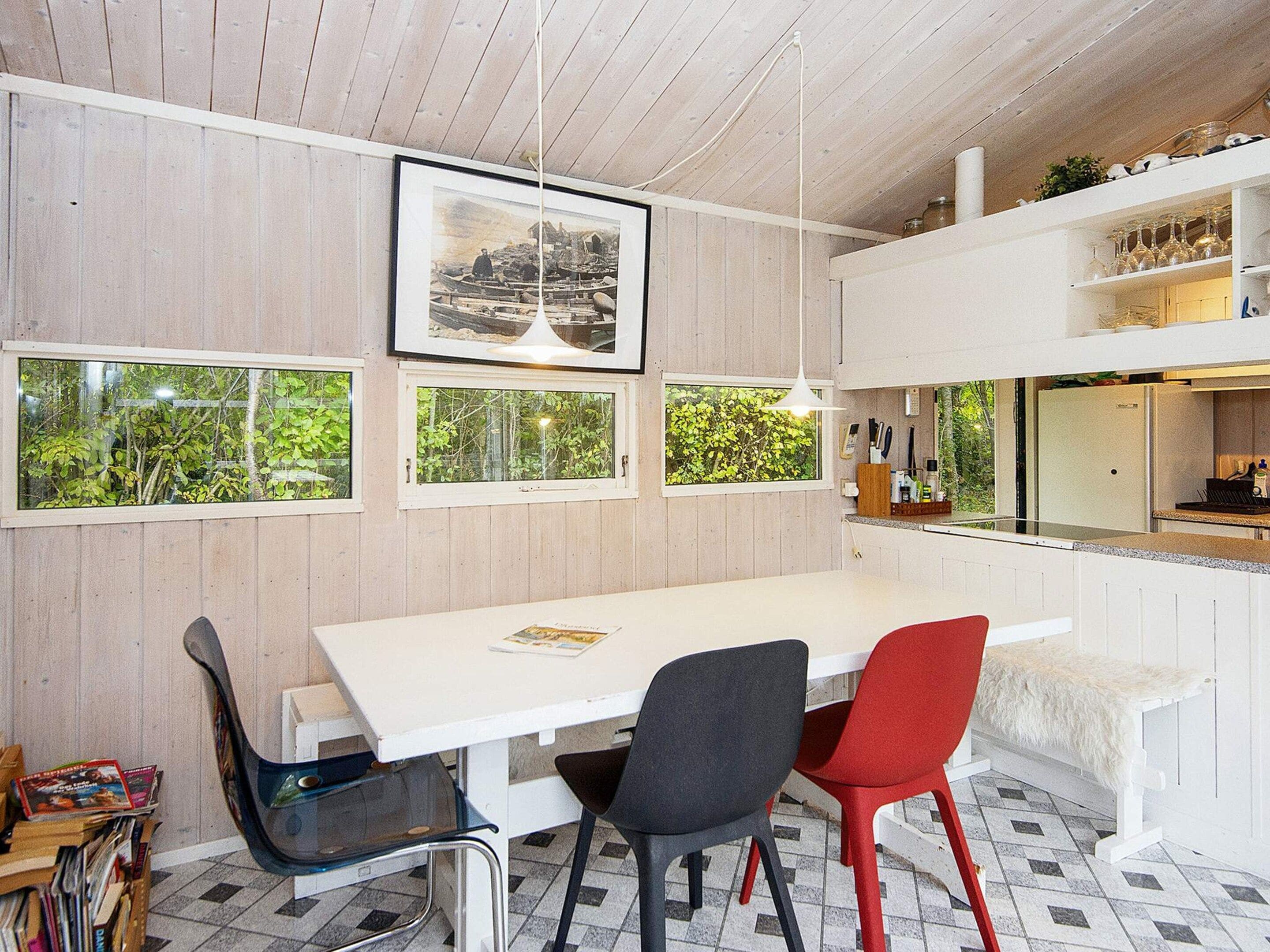 A dining area with a white table, black and red chairs, and a framed picture above.