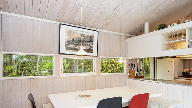 A dining area with a white table, black and red chairs, and a framed picture above.