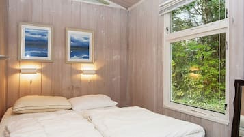A bedroom with a bed, two wall-mounted lights, and a window with a view of greenery.