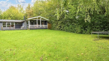 A house with a covered porch, a lawn, and a trampoline.