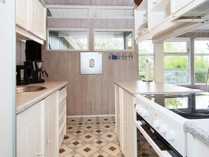 Une cuisine de taille réduite, équipée d’une cuisinière, d’un évier et d’une fenêtre.