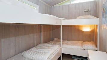 A bunk bed room with wooden walls and a window.