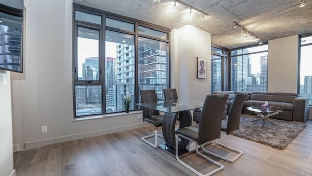 A modern office space with a glass table, chairs, and a sofa. Large windows offer a view of the cityscape. - beauti 2 bedroom with 2 bathroom condo in downtown (Calgary)