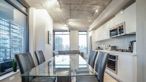 A modern kitchen with a glass dining table and chairs, a built-in oven, and a microwave. - beauti 2 bedroom with 2 bathroom condo in downtown (Calgary)