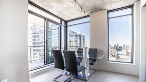Un espacio de oficina moderno con ventanas amplias, una mesa de cristal y dos sillas negras.