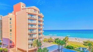 Ein Mehrstöckiges Hotel mit Balkonen mit Blick auf einen Strand.