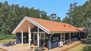 Une maison à deux étages dotée d’un patio couvert, d’un barbecue et de meubles d’extérieur.